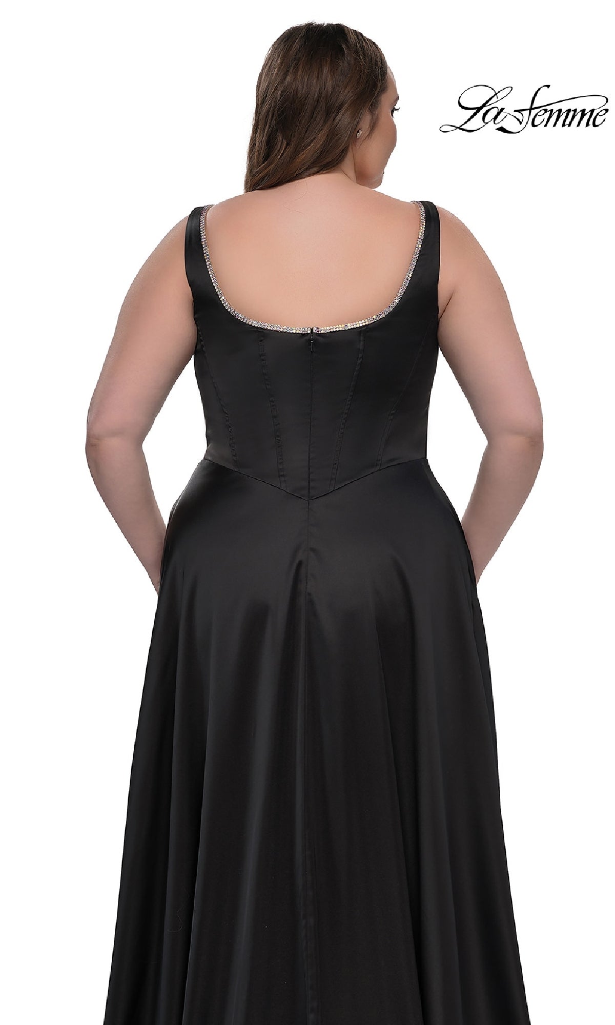 A woman models the Plus-Size Classic Long Prom Gown: La Femme 33026, a long black sleeveless dress with a low back and subtle silver trim, shown from behind against a white background.